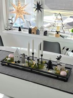 a table with candles and decorations on it in front of a window at christmas time