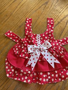 a red and white polka dot dress on a wooden floor with a bow at the back