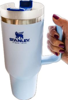 a woman's hand holding a blue and white coffee cup with the stanley logo on it