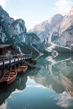 several boats are docked in the water near mountains