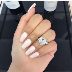 a woman's hand holding a diamond ring and some bottles of wine on the table