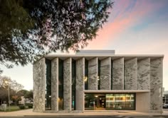 an architecturally designed building on the corner of a street in front of a tree