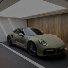 a green sports car parked in a parking lot next to a wall with wood paneling