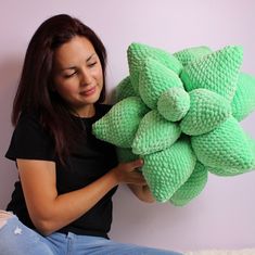 a woman sitting on the floor holding a green stuffed flower