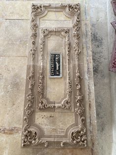 an ornately carved frame on the side of a building with a plaque in it