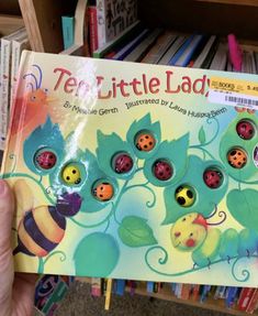 a person holding up a children's book with ladybugs and leaves on it