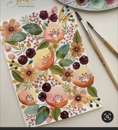 a card with flowers on it next to some paintbrushes