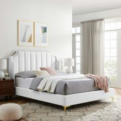 a white bed sitting in a bedroom on top of a hard wood floor next to a window