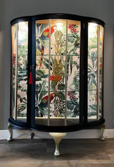 a glass display case in the corner of a room with flowers and plants on it