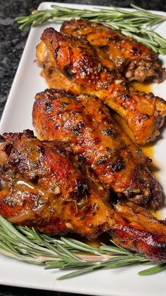 grilled chicken wings with rosemary garnish on a white plate