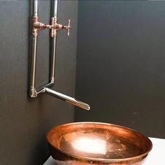 a large copper bowl sitting on top of a counter next to a faucet