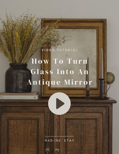 an antique mirror sitting on top of a wooden cabinet next to a vase with flowers