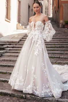 a woman in a wedding dress standing on some steps