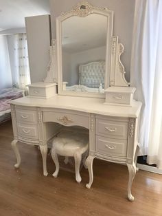 a white dressing table with a mirror and stool