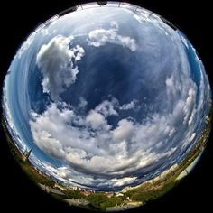 a fish eye view of the sky with clouds in it's center and some buildings on the other side