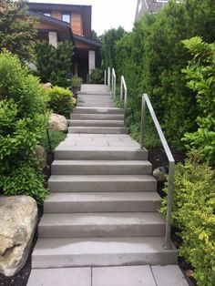 a set of stairs leading up to a house with trees and bushes in the background