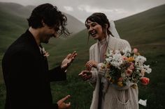 a man and woman standing next to each other in front of a field with flowers