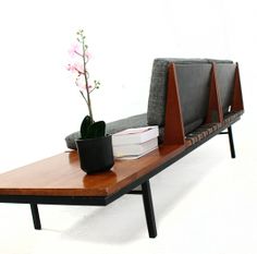 a wooden table with a plant and books on it next to a gray couch cushion