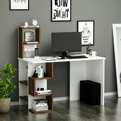 a desk with a computer on it in front of some pictures and a potted plant