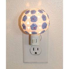 a light that is on the side of a wall next to a power outlet with flowers painted on it