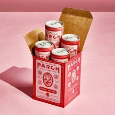 six cans of peach tea in a red box on a pink surface with brown paper