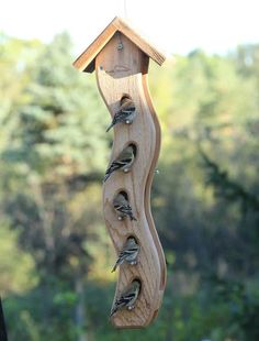 a bird feeder hanging from the side of a building with birds on it's sides