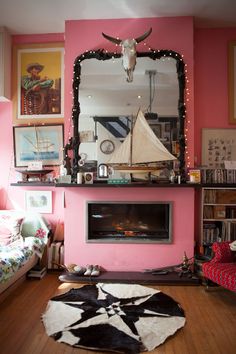 a living room with pink walls and a cow hide rug in front of the fireplace