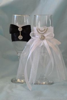 two wine glasses with bows and pearls on the side, one is black and one is white