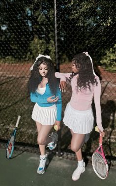 two women standing next to each other holding tennis racquets