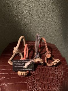 there are three rope toys on top of a crocodile skin surface with a name tag