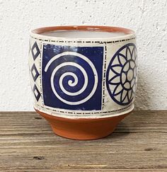 a blue and white planter sitting on top of a wooden table next to a wall