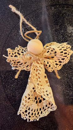 an angel ornament made from crochet and twine on a table