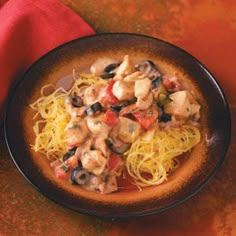 a black bowl filled with pasta and mushrooms on top of a table next to a red napkin