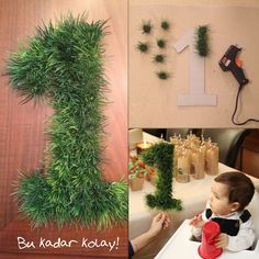 a baby sitting at a table in front of a number one made out of fake grass