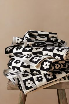 black and white patterned towels stacked on top of each other in front of a beige wall