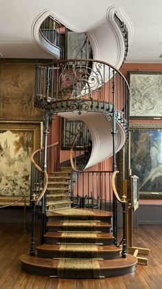 a spiral staircase in an old building with paintings on the walls and wooden floors,