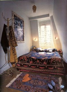 a room with a bed and rugs on the floor next to a window in it