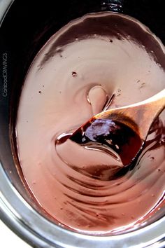 melted chocolate in a silver pot with a wooden spoon sticking out of the top and bottom