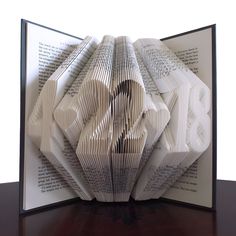 an open book with folded pages sitting on top of a table