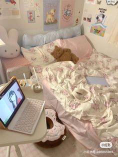 a laptop computer sitting on top of a desk next to a bed with pink sheets