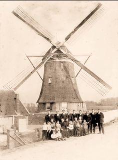 a group of people standing in front of a windmill