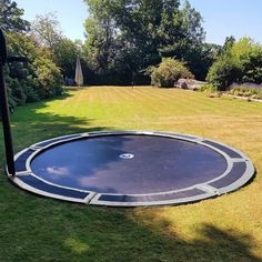 an empty trampoline in the middle of a yard