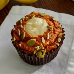 a cupcake with white frosting and pumpkin seeds on top sitting on a napkin