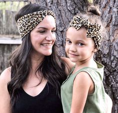 two girls standing next to each other in front of a tree wearing headbands