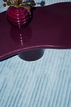 a vase with flowers sitting on top of a purple table