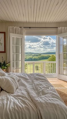 a large bed sitting in a bedroom next to an open window with a view of the countryside