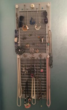 a wall mounted jewelry rack with many necklaces and earrings hanging on it's sides