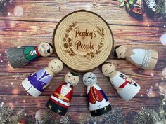 an assortment of wooden peg dolls sitting in front of a christmas decoration on a table