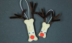 two reindeer head ornaments hanging from strings on a gray surface with red noses and nose