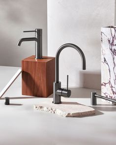 two faucets and a soap dispenser on a white countertop